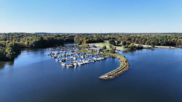 Aerial view of a marina with docked boats and a curved stone breakwater on Alum Creek Lake in Delaware County, Ohio